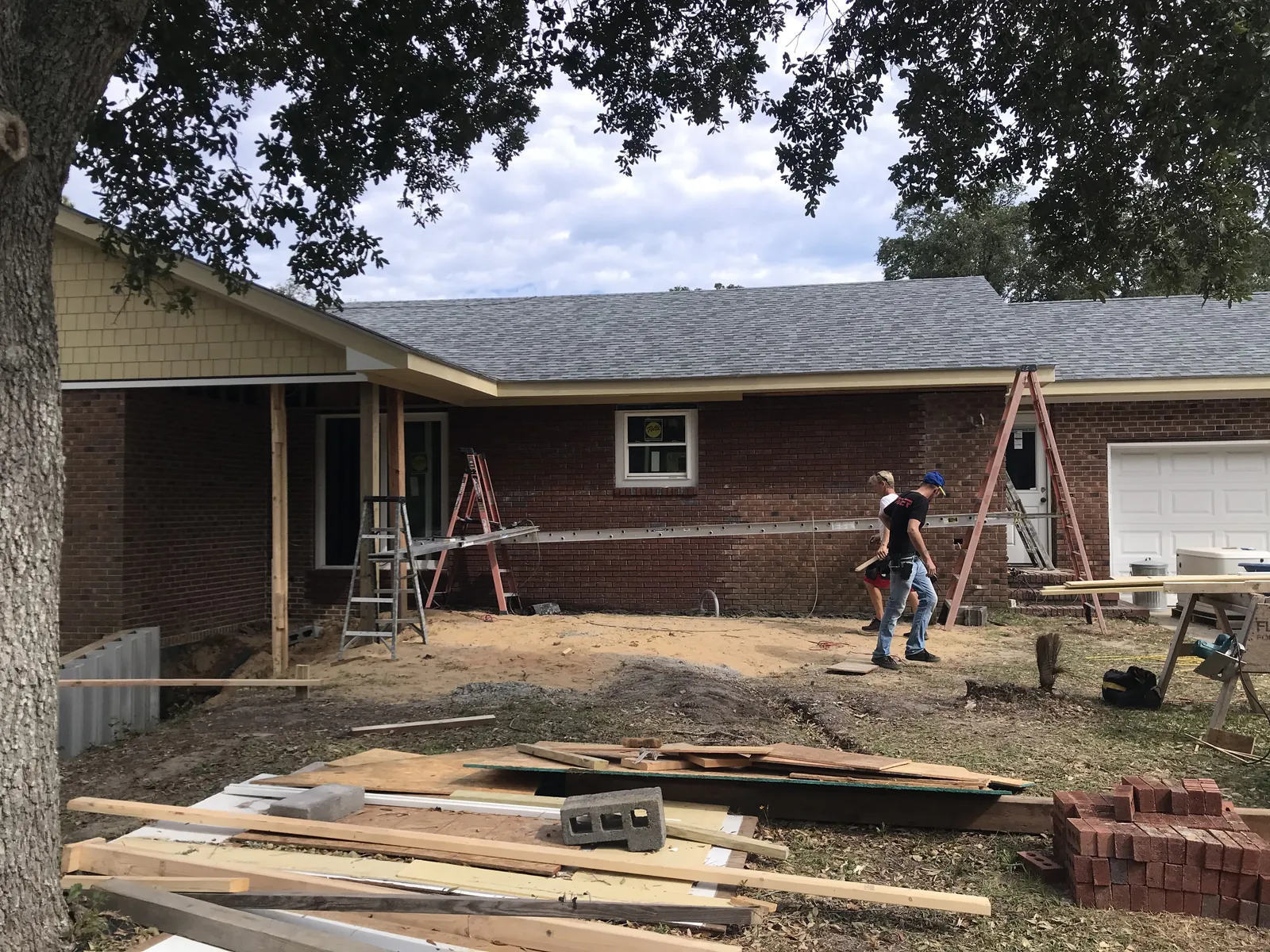 Long single-story brick home with a lumber delivery during an addition in Brunswick County, NC